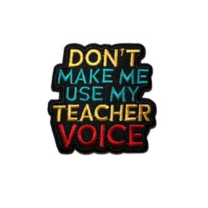 May include: Embroidered patch with the text "DON'T MAKE ME USE MY TEACHER VOICE". The patch has a black border with yellow, teal, and red lettering. The patch is rectangular with rounded corners.
