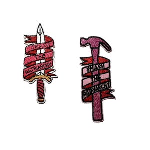 May include: Two embroidered patches on a white background. One patch features a sword with a red banner that reads "SMASH THE PATRIARCHY." The other patch is a pink hammer with a similar banner. Both patches have black outlines.