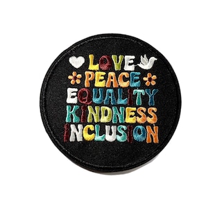 May include: Round black patch embroidered with the words "LOVE, PEACE, EQUALITY, KINDNESS, INCLUSION" in colorful letters. A white heart, dove, and flower accents the text. The patch is likely for clothing or accessories.