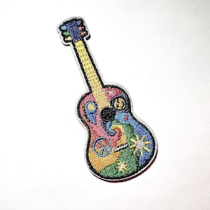 May include: Embroidered patch in the shape of a colorful acoustic guitar. The guitar features a rainbow of colors, including red, yellow, blue, and green, with peace signs and sunbursts. The patch has a white border.