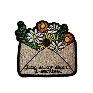 May include: Embroidered patch featuring a tan envelope overflowing with colorful flowers. The flowers include white daisies, yellow sunflowers, and orange blooms. The patch has a black border and the text "Long story short, I survived" in black.