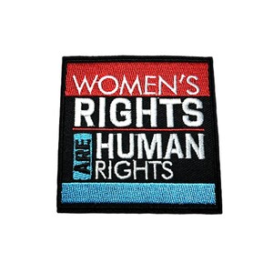 May include: Embroidered patch with the text "WOMEN'S RIGHTS ARE HUMAN RIGHTS" in white, red, and blue. The patch is square with a black border and a blue stitched bottom.
