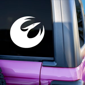 Könnte beinhalten: Ein weißer Aufkleber mit dem Symbol der Rebellenallianz auf einem rosafarbenen Auto. Das Symbol ist ein stilisierter Vogel im Flug mit ausgebreiteten Flügeln.