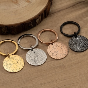 May include: Four keychains with different colored metal finishes. Each keychain features a round disc with a constellation design.