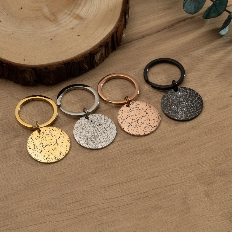 May include: Four keychains with different colored metal finishes. Each keychain features a round disc with a constellation design.