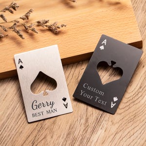 Puede incluir: Dos abridores de botellas metálicos con forma de carta de As de Picas. Uno es plateado con "Gerry BEST MAN" grabado. El otro es negro con "Custom Your Text" grabado. Ambos tienen un recorte en forma de pica.