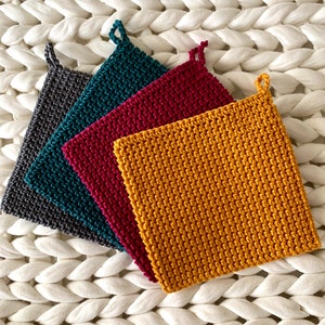 May include: Four crocheted pot holders in different colors: gray, teal, burgundy, and mustard yellow. Each pot holder has a loop for hanging.