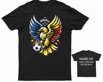 Könnte beinhalten: Schwarzes T-Shirt mit einem Grafikdruck eines goldenen Adlers mit ausgebreiteten Flügeln, der einen Fußball hält. Die Flügel des Adlers sind mit den Farben der rumänischen Flagge verziert. Der Text "ROMANIA" steht über dem Adler.