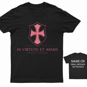 May include: Black t-shirt featuring a pink Knights Templar cross and shield design. The text "IN VIRTUTE ET ARMIS" and "KNIGHTS TEMPLAR" is printed below the design.