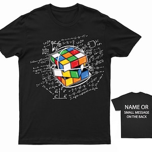 May include: Black t-shirt featuring a white graphic of a Rubik's Cube surrounded by mathematical equations. "NAME OR SMALL MESSAGE ON THE BACK" is printed on the back of the shirt.
