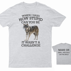 K&ouml;nnte beinhalten: Graues T-Shirt mit einem Wolf-Motiv und dem Text "WHEN I SAID HOW STUPID CAN YOU BE IT WASN'T A CHALLENGE". Auf der R&uuml;ckseite des Shirts steht "NAME OR SMALL MESSAGE ON THE BACK".