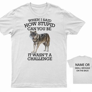K&ouml;nnte beinhalten: Wei&szlig;es T-Shirt mit einem Wolf-Motiv und dem Text "When I said how stupid can you be it wasn't a challenge". Auf der R&uuml;ckseite des Shirts steht "Name or small message on the back".