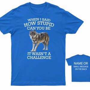 K&ouml;nnte beinhalten: Ein k&ouml;nigsblaues T-Shirt mit einer wei&szlig;en Wolfgrafik und dem Text "WHEN I SAID HOW STUPID CAN YOU BE IT WASN'T A CHALLENGE". Die R&uuml;ckseite des Shirts tr&auml;gt den Text "NAME OR SMALL MESSAGE ON THE BACK".