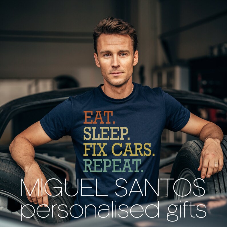 Puede incluir: Un hombre lleva una camiseta azul marino con el texto "EAT. SLEEP. FIX CARS. REPEAT." en letras retro de colores. El texto est&aacute; centrado en la camiseta. El hombre est&aacute; de pie en un garaje con un neum&aacute;tico de coche en el fondo. El texto "MIGUEL SANTOS regalos personalizados" est&aacute; en la parte inferior de la imagen.