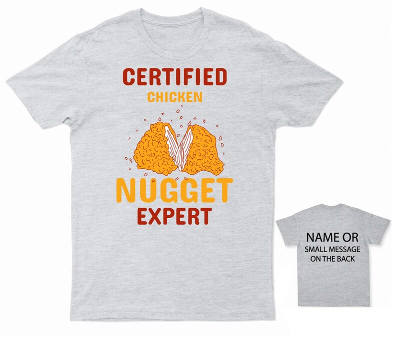 Op de afbeelding: Een grijs T-shirt met de tekst "CERTIFIED CHICKEN NUGGET EXPERT" in rood en oranje. Een cartoon afbeelding van een kippen nugget bevindt zich in het midden van het shirt. De achterkant van het shirt is grijs met de tekst "NAME OR SMALL MESSAGE ON THE BACK" in zwart.