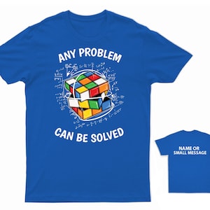 May include: A blue t-shirt with a white graphic of a Rubik's Cube surrounded by mathematical equations and the text "ANY PROBLEM CAN BE SOLVED".