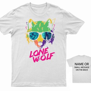 May include: White t-shirt with a colorful graphic of a wolf wearing sunglasses and the text "LONE WOLF" in pink letters.