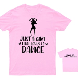 May include: Pink t-shirt with a black silhouette of a woman dancing and the text "Just a girl that loves to dance".
