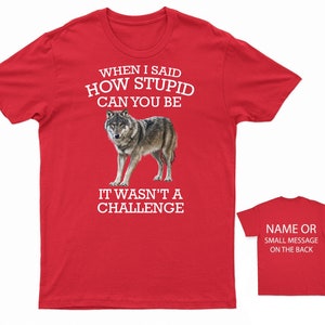 K&ouml;nnte beinhalten: Rotes T-Shirt mit einem wei&szlig;en Wolf-Motiv und dem Text "WHEN I SAID HOW STUPID CAN YOU BE IT WASN'T A CHALLENGE". Auf der R&uuml;ckseite des Shirts steht "NAME OR SMALL MESSAGE ON THE BACK".
