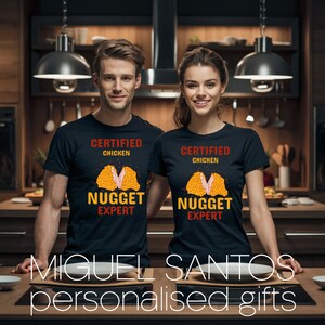Op de afbeelding: Twee zwarte T-shirts met een afbeelding van een kipnugget en de tekst "Certified Chicken Nugget Expert".