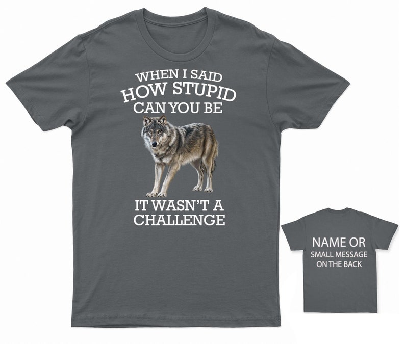 K&ouml;nnte beinhalten: Ein dunkelgraues T-Shirt mit einer wei&szlig;en Wolfgrafik und dem Text "WHEN I SAID HOW STUPID CAN YOU BE IT WASN'T A CHALLENGE". Auf der R&uuml;ckseite des Shirts steht "NAME OR SMALL MESSAGE ON THE BACK".
