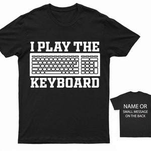 May include: Black t-shirt with white text that reads "I Play The Keyboard" and a graphic of a computer keyboard.