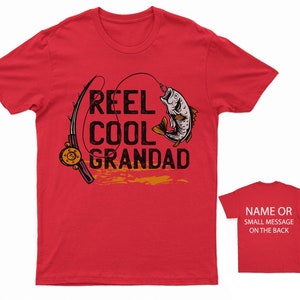May include: Red t-shirt with a fishing rod and fish graphic. The text "Reel Cool Grandad" is printed on the shirt.