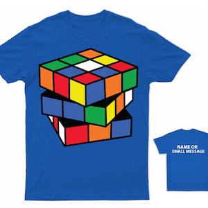May include: A royal blue t-shirt featuring a colourful Rubik's Cube design. The cube is stacked three high and is in a partially solved state. The back of the shirt is plain blue with the text "NAME OR SMALL MESSAGE" in white.