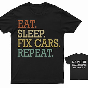 Puede incluir: Camiseta negra con el texto "EAT. SLEEP. FIX CARS. REPEAT." en un esquema de colores retro. El texto est&aacute; en negrita, fuente sin serifas. La camiseta tiene cuello redondo y mangas cortas.