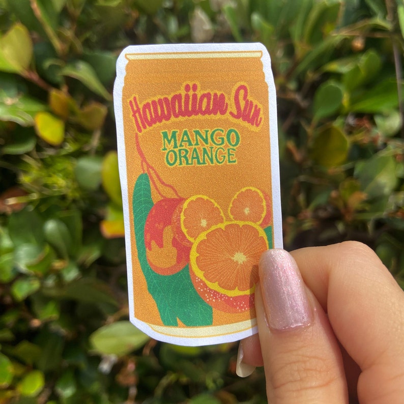 May include: A sticker featuring a vintage-style Hawaiian Sun Mango Orange can design. The can is orange with the words "Hawaiian Sun" in red script and "Mango Orange" in green. The design includes illustrations of mangoes and orange slices.