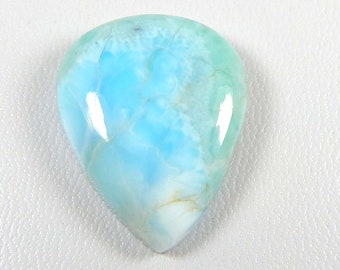 May include: A light blue, white, and green cabochon gemstone with a pear shape. The gemstone has a cloudy, marbled appearance.