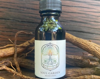 Op de afbeelding: Een donker glazen flesje met een druppelaar en een wit etiket. Het etiket heeft een gestileerde boom met een groene, blauwe en paarse kleurstelling. De tekst "SOUL GARDEN MEDICINES" staat op het etiket gedrukt.