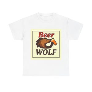 Op de afbeelding: Wit T-shirt met een afbeelding van "Beer WOLF". Het ontwerp toont een bruine wolf die uit een oranje bierpul drinkt. De afbeelding staat in een zwart omrand, lichtgeel rechthoek.