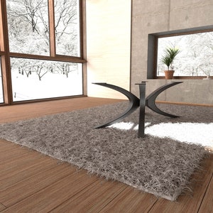 Puede incluir: Una mesa de centro de metal negro con una base en forma de X &uacute;nica se encuentra sobre una alfombra gris esponjosa en una sala de estar moderna. La mesa est&aacute; situada frente a una ventana grande con vista a un paisaje nevado.