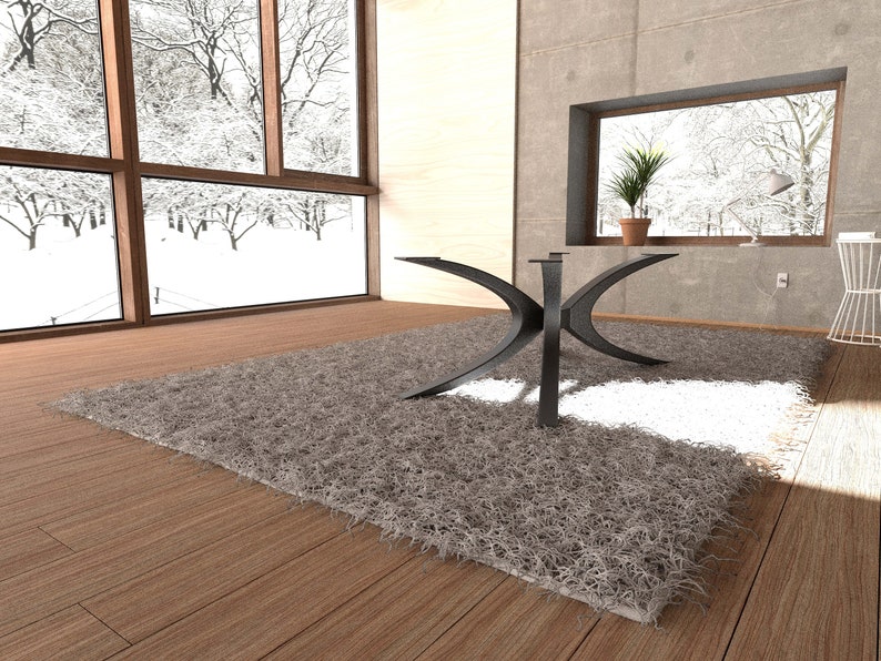 Puede incluir: Una mesa de centro de metal negro con una base en forma de X &uacute;nica se encuentra sobre una alfombra gris esponjosa en una sala de estar moderna. La mesa est&aacute; situada frente a una ventana grande con vista a un paisaje nevado.