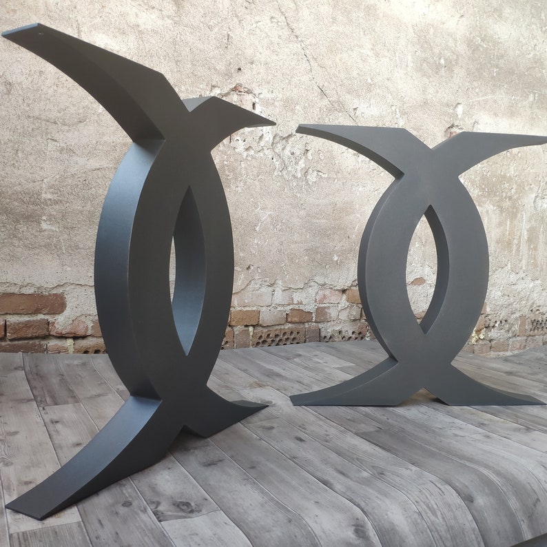 Puede incluir: Dos patas de mesa de metal negro en forma de X con un dise&ntilde;o curvo. Las patas son de metal grueso y tienen un acabado liso y mate.