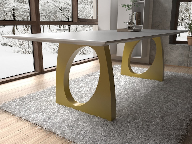 May include: A white rectangular dining table with a gold metal base. The base has a unique oval cutout design. The table is on a white shag rug.