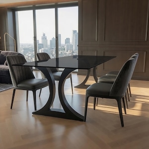 May include: A rectangular dining table with a dark glass top and a black curved base, accompanied by four dark gray upholstered chairs featuring vertical channel tufting on the backrests and solid dark wooden legs arranged around the table.