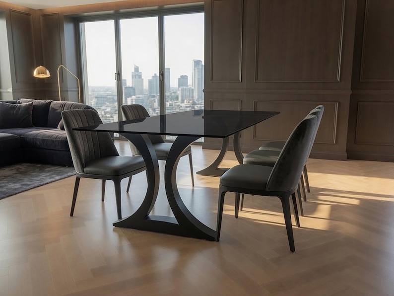 May include: A rectangular dining table with a dark glass top and a black curved base, accompanied by four dark gray upholstered chairs featuring vertical channel tufting on the backrests and solid dark wooden legs arranged around the table.