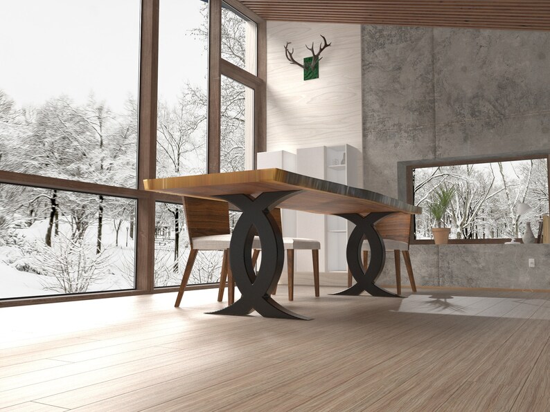 Puede incluir: Una mesa de comedor de madera con una tapa de borde vivo y patas de metal negro. La mesa est&aacute; ubicada en un comedor moderno con grandes ventanales con vistas a un bosque nevado.