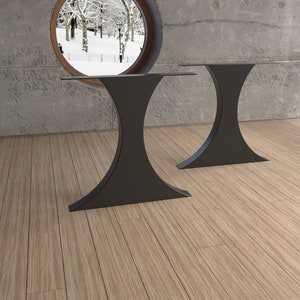 May include: Two black metal table legs with a unique hourglass shape. The legs are made of sturdy metal and have a sleek, modern design.