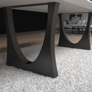 May include: Close-up of a black metal table leg with a curved design. The leg is on a white shag rug.
