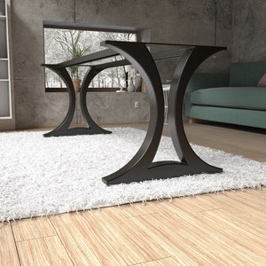May include: A black metal table base featuring two large, curved, arch-shaped supports connected by a horizontal frame. The structure has a smooth, matte finish and a wide, stable footprint designed to support a tabletop surface.