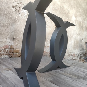 Puede incluir: Dos patas de mesa de metal negro con un dise&ntilde;o &uacute;nico y abstracto. Las patas son de metal grueso y resistente y tienen un acabado liso y mate.