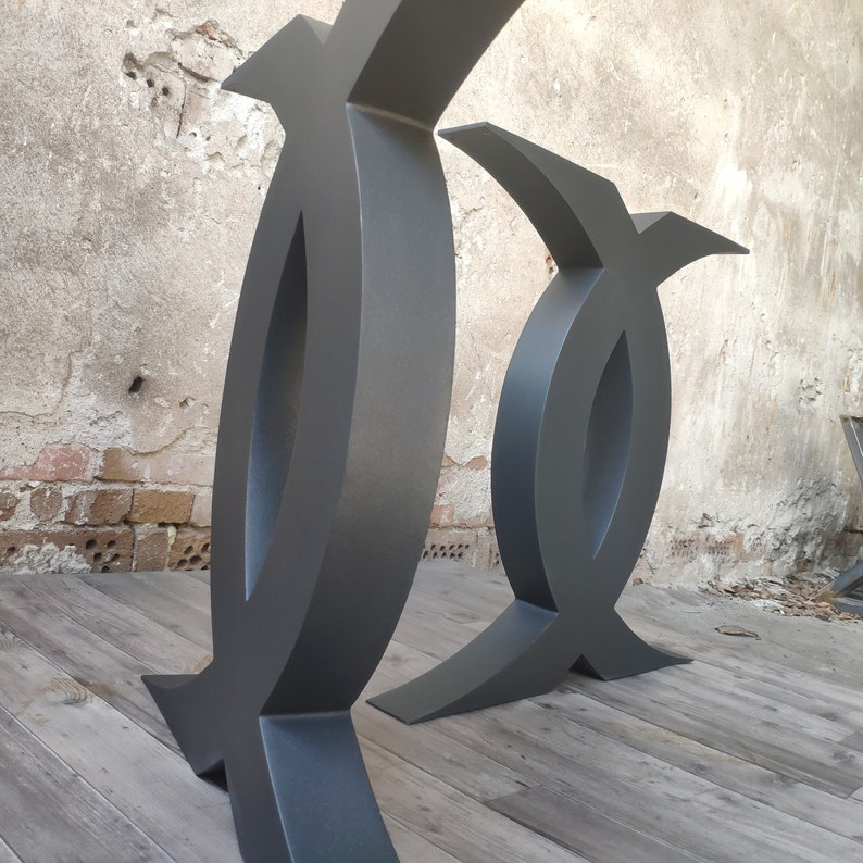 Puede incluir: Dos patas de mesa de metal negro con un dise&ntilde;o &uacute;nico y abstracto. Las patas son de metal grueso y resistente y tienen un acabado liso y mate.