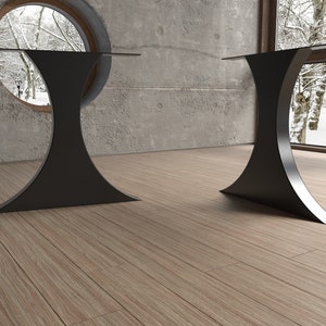May include: Two black metal table legs with a glass tabletop. The legs are shaped like an hourglass and have a wide base.