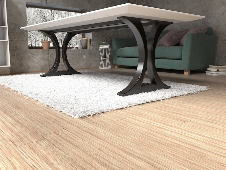 May include: A dining table featuring a thick, rectangular white tabletop supported by two black, curved metal legs. The base of each leg forms an arch shape that connects to the floor, providing a stable foundation for the flat, smooth surface.