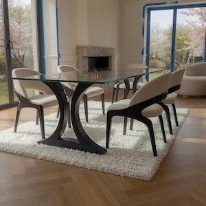 May include: A rectangular dining table with a clear glass top and a black curved base, accompanied by four chairs featuring cream-colored upholstered seats and backrests with dark wood frames, all positioned on a white shaggy area rug.