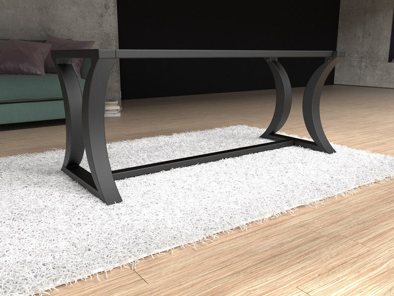 Op de afbeelding: Een rechthoekige tafel met een helder glazen blad ondersteund door een matzwart metalen frame. De basis bestaat uit vier gebogen, C-vormige poten die met elkaar verbonden zijn door een horizontale steunbalk voor dit meubelstuk.