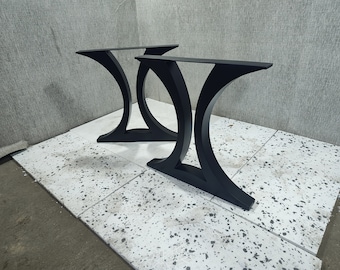 May include: Two black metal table legs with a curved design. The legs are made of sturdy metal and have a black finish.